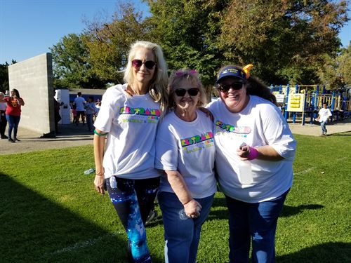 3 adults standing on lawn wearing matching white walk-a-thon tshirts